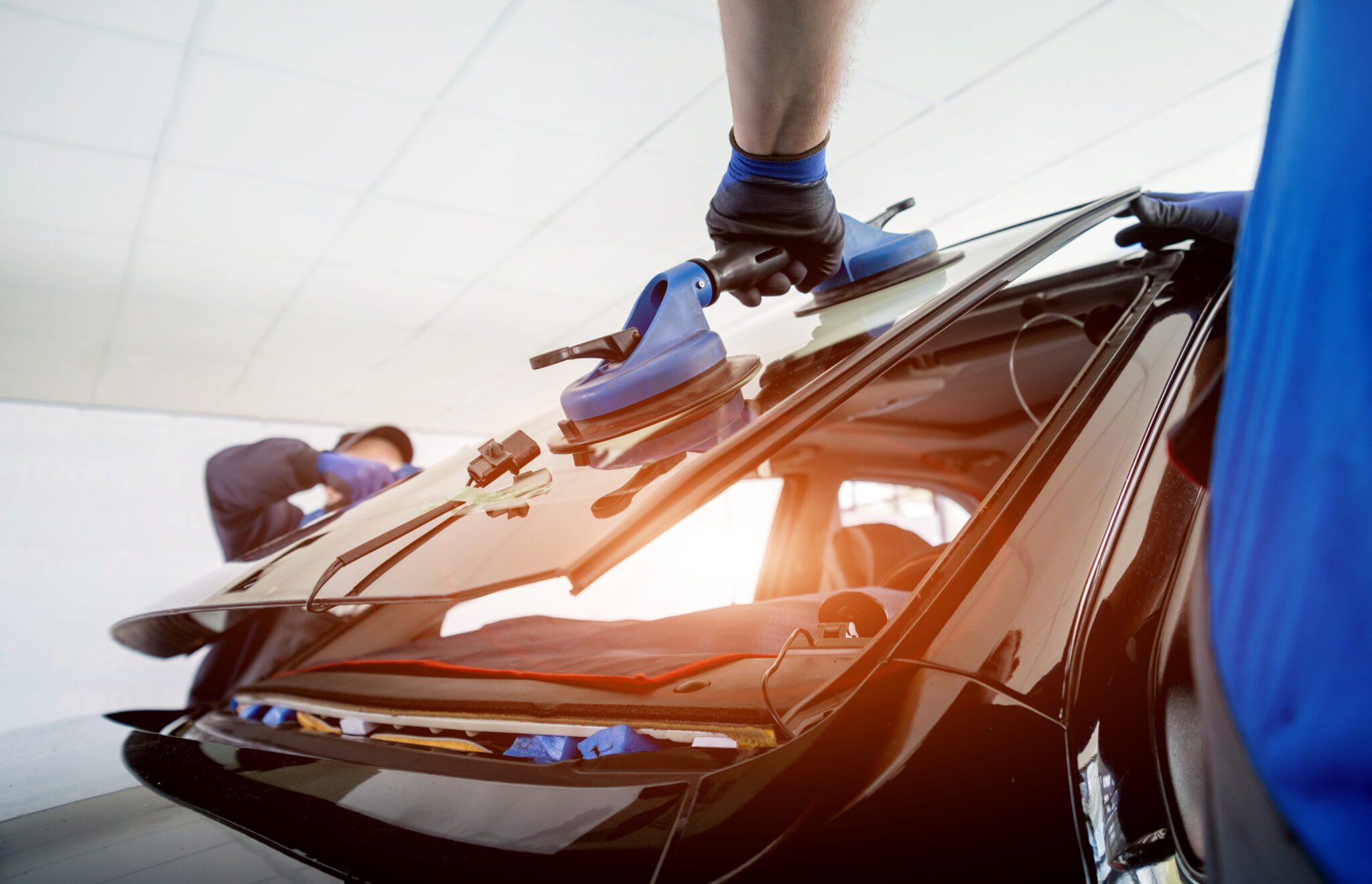 Auto glass technician removing windshield with suction tool in Hampton Roads